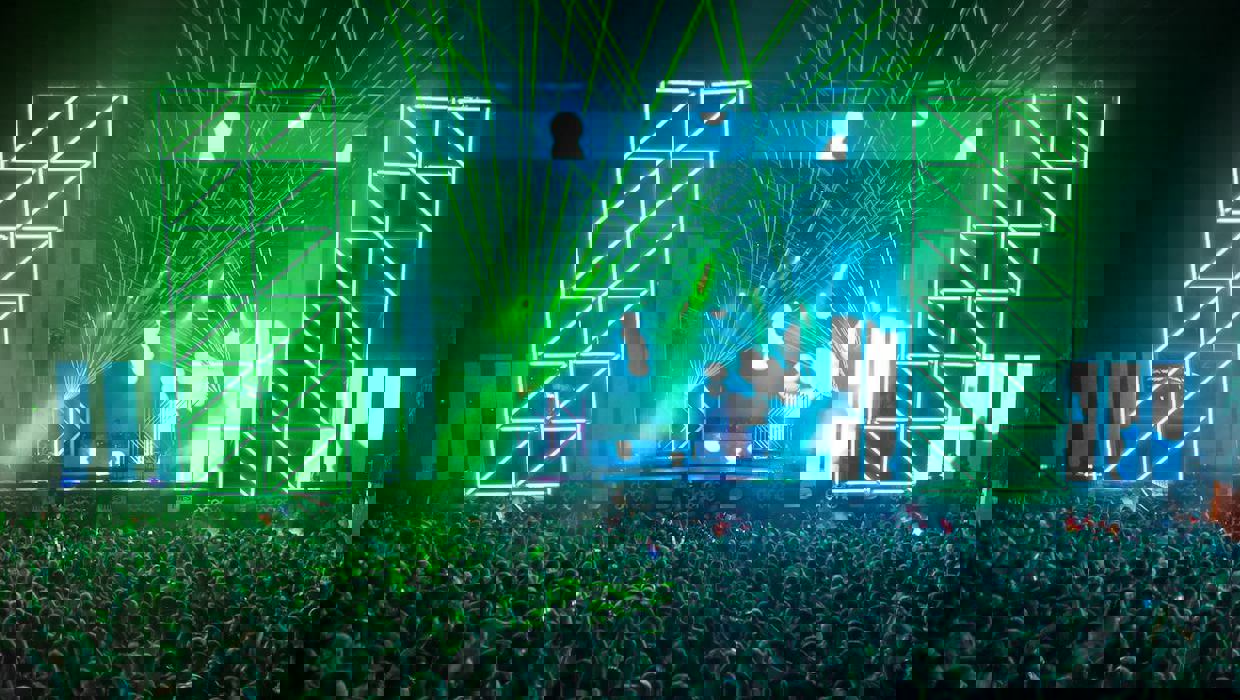 huge festival stage with crowd in green light